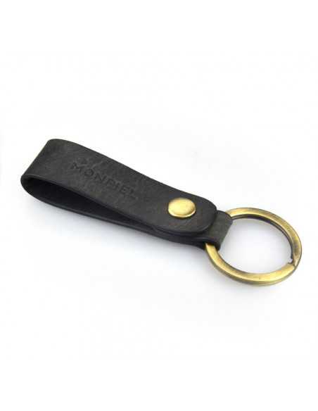 Black unisex leather keychain with logo detail, slightly tilted on a white background - MONPIEL Black unisex leather keychain with logo detail, slightly tilted on a white background - MONPIEL