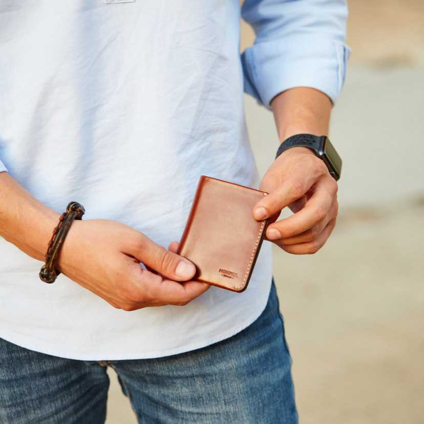 Small Havana leather men’s wallet with billfold, front view, slightly tilted, outdoor photo - MONPIEL