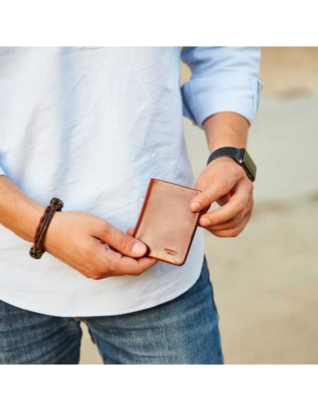 Petit portefeuille homme en cuir havane avec compartiment à billets, frontal et légèrement incliné, photo en extérieur - MONPIEL Petit portefeuille homme en cuir havane avec compartiment à billets, frontal et légèrement incliné, photo en extérieur - MONPIEL