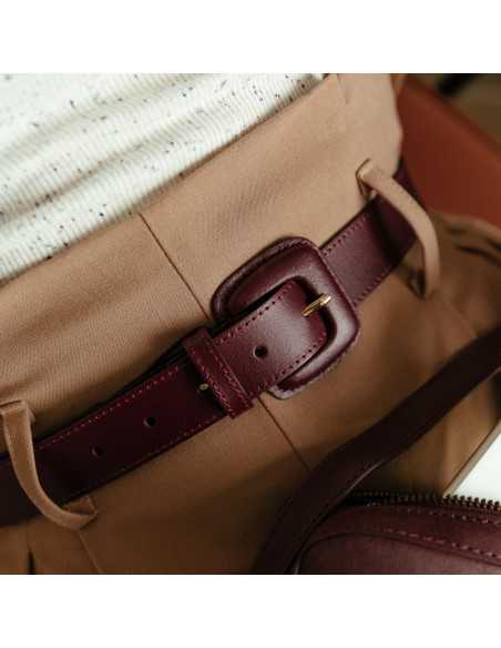 Burgundy leather women’s belt with covered buckle, buckle detail worn over brown pants - MONPIEL Burgundy leather women’s belt with covered buckle, buckle detail worn over brown pants - MONPIEL