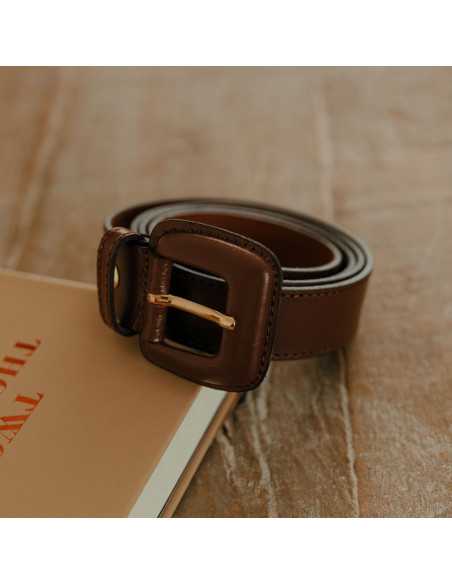 Brown leather women’s belt with covered buckle coiled on a book - MONPIEL Brown leather women’s belt with covered buckle coiled on a book - MONPIEL