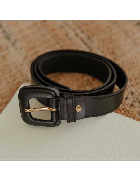 Black leather women’s belt with covered buckle coiled on a notebook - MONPIEL Black leather women’s belt with covered buckle coiled on a notebook - MONPIEL