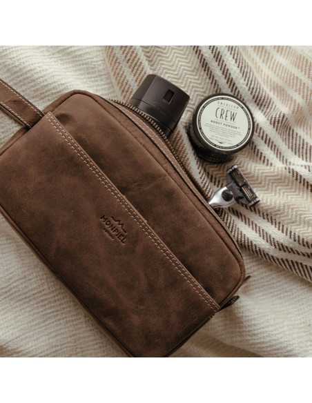 Men’s brown leather toiletry bag with front pocket, interior capacity detail, open zipper, resting on a rug - MONPIEL