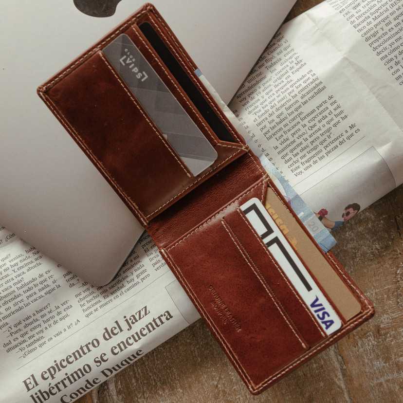 Havana leather wallet for men, open, showing slot details, resting on a laptop and newspaper - MONPIEL