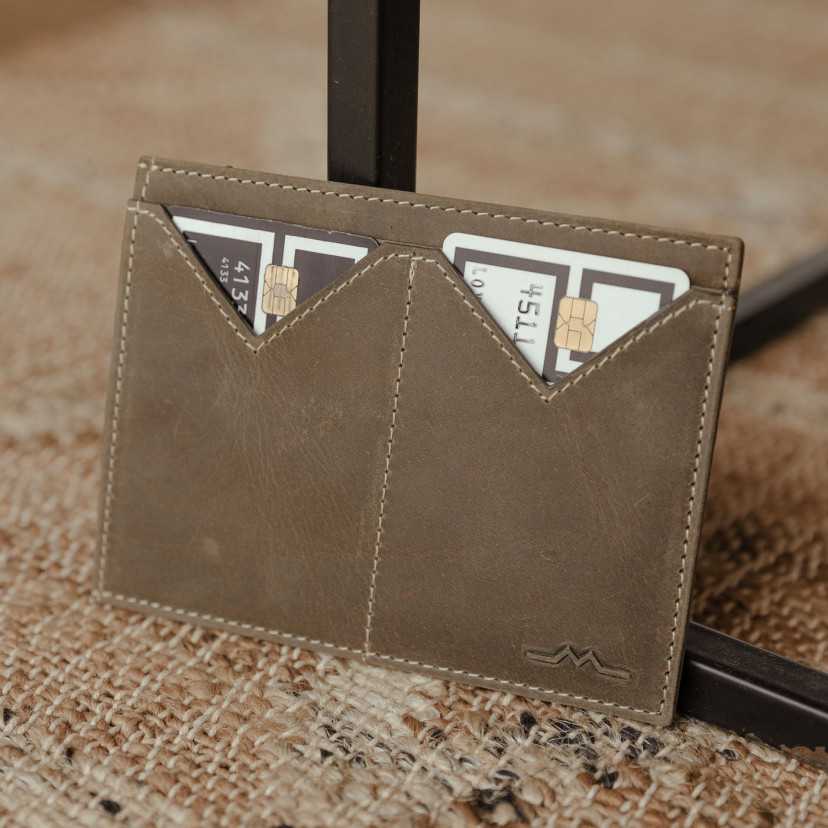 Men’s green leather passport holder with card slots, resting on a table - MONPIEL