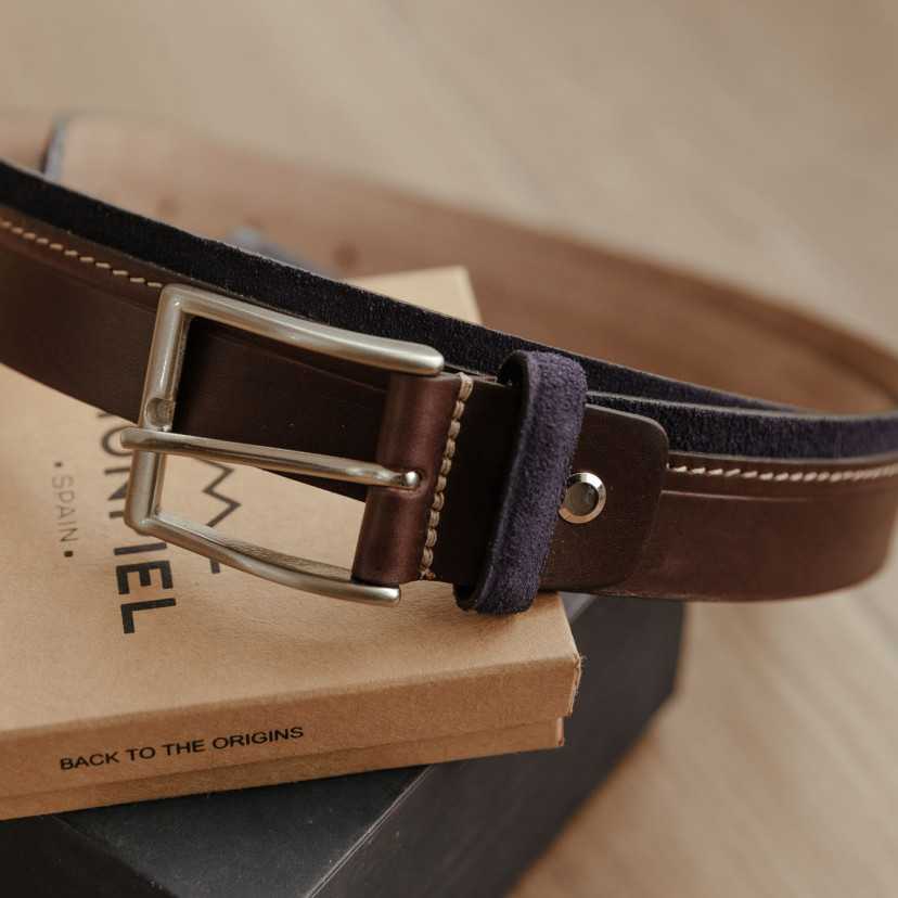 Navy leather and suede belt, resting on boxes, focused on the buckle detail - MONPIEL