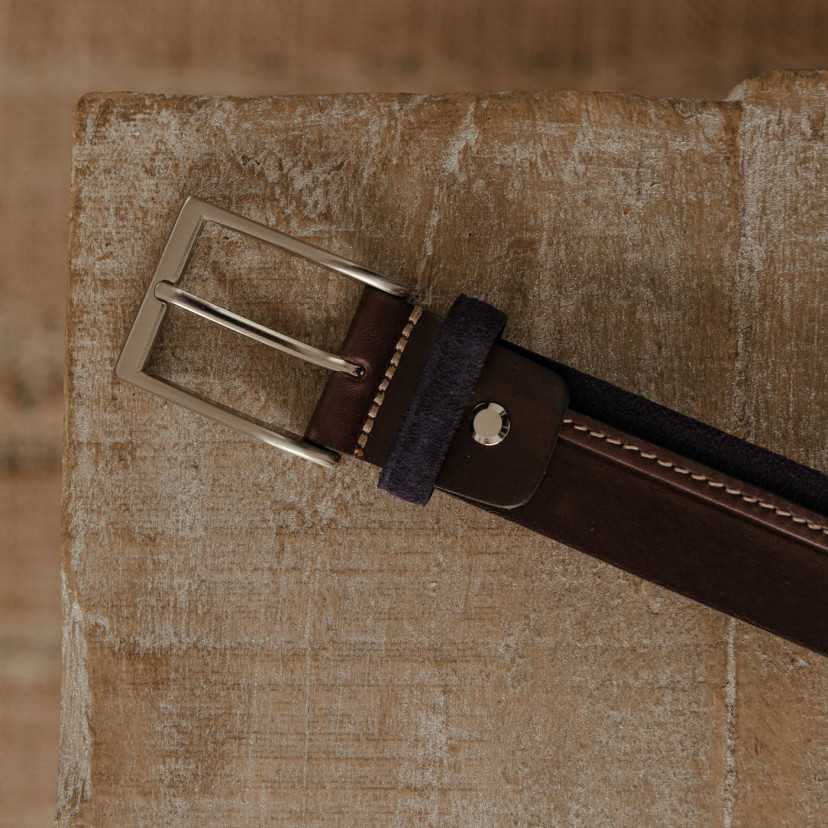 Navy leather and suede belt, buckle detail, resting on a table - MONPIEL