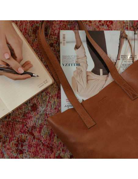 Shopper-Tasche in Lederfarbe mit Logodetail, Zeitschrift im Inneren, auf einem Teppich liegend - MONPIEL