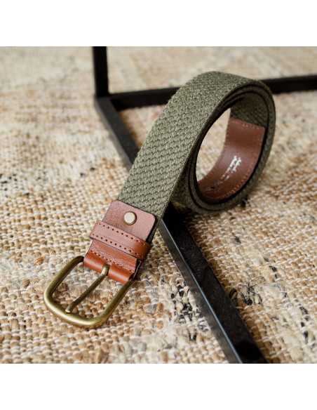 Green leather men’s elastic belt, coiled with buckle detail, resting on a rug - MONPIEL Green leather men’s elastic belt, coiled with buckle detail, resting on a rug - MONPIEL