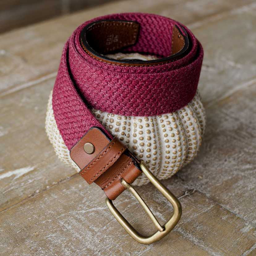 Men’s burgundy elastic leather belt, coiled, resting on ceramic - MONPIEL