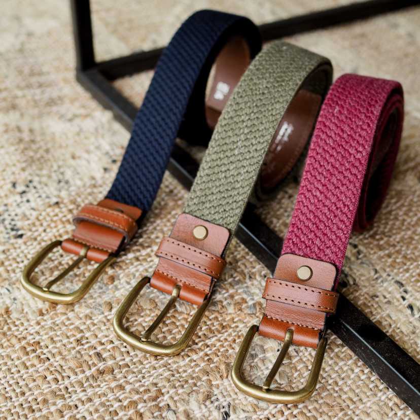 Men’s elastic leather belts in burgundy, navy, and green, coiled, with buckle detail, on a rug - MONPIEL