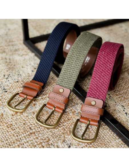 Ceintures élastiques homme en cuir bordeaux, bleu marine et vert, enroulées avec détail de la boucle sur un tapis - MONPIEL