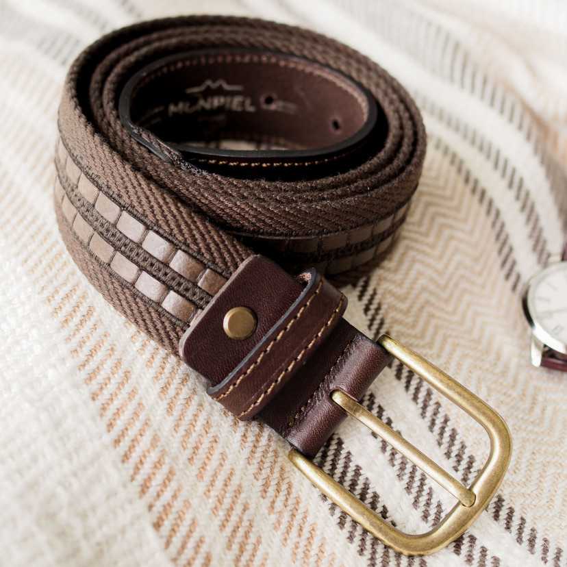 Men’s brown canvas and leather belt, coiled on a blanket, focusing on the buckle - MONPIEL
