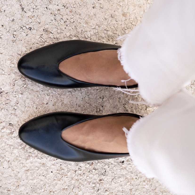 Black heeled ballet flats, top-down view, feet resting on the floor - MONPIEL