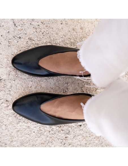 Black heeled ballerina shoes, detail photo from above with feet resting on the floor - MONPIEL Black heeled ballerina shoes, detail photo from above with feet resting on the floor - MONPIEL