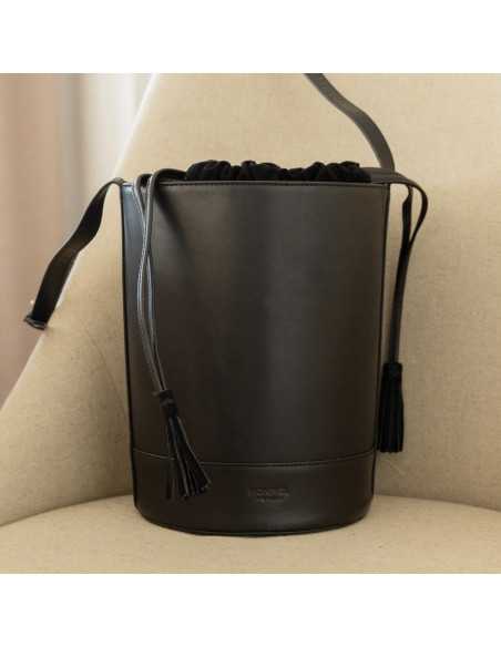 Runde schwarze Lederhandtasche in Eimerform, Vorderansicht auf einem Sessel - MONPIEL