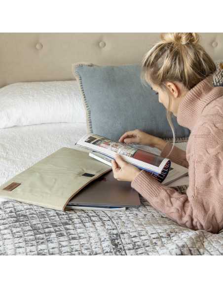 Custodia per laptop da 15" pollici color beige su un letto, con la modella che legge una rivista - MONPIEL