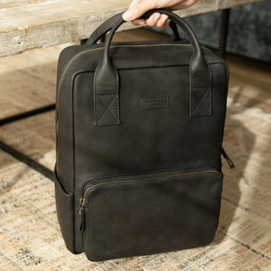 Mochila de couro marrom sendo aberta no chão, com detalhe interno - MONPIEL 2