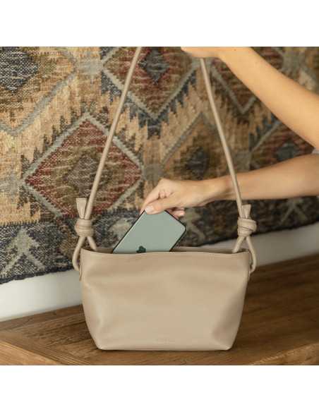 Bolso nudos pequeño de piel en color topo con vista frontal con detalle guardando el móvil - MONPIEL Bolso nudos pequeño de piel en color topo con vista frontal con detalle guardando el móvil - MONPIEL