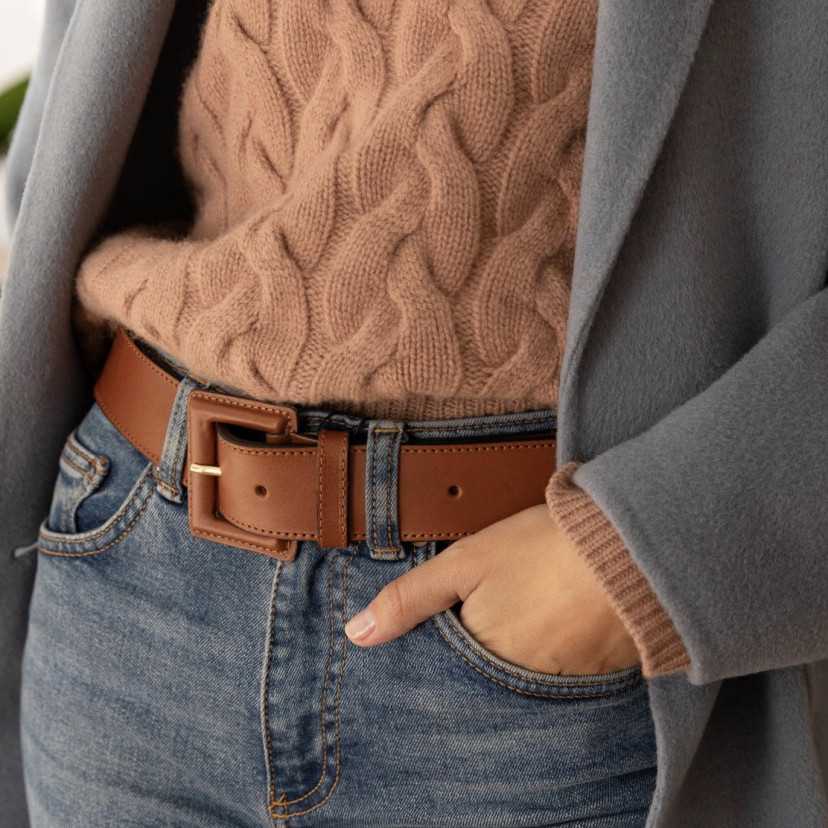 Wide women’s leather belt with covered buckle in tan, worn over jeans, perspective view centered on buckle - MONPIEL