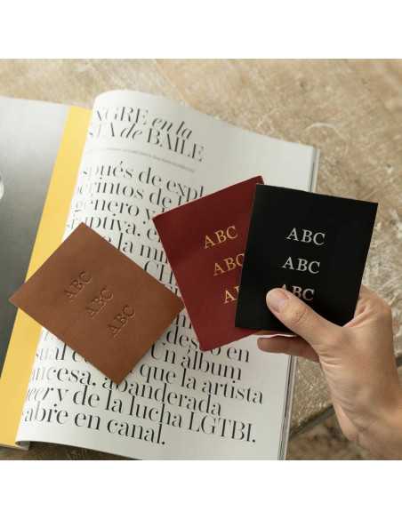 Iniciais personalizadas de três letras gravadas a fogo, ouro e níquel, sobre o fundo de uma revista - MONPIEL