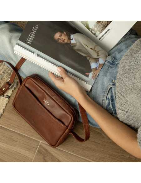 Iniziali personalizzate incise in oro su una borsa in pelle color cuoio appoggiata a terra - MONPIEL