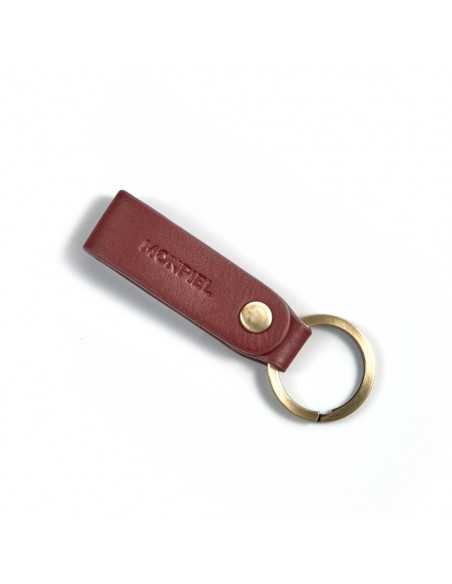 Burgundy and tan leather pocket keychain, closed and tilted on a white background - MONPIEL Burgundy and tan leather pocket keychain, closed and tilted on a white background - MONPIEL