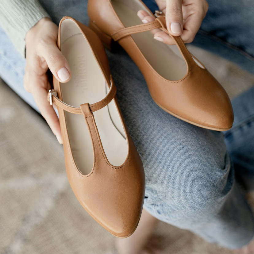 Women's Marieta leather Mary Janes in tan, shown from above held with hands on jeans - MONPIEL