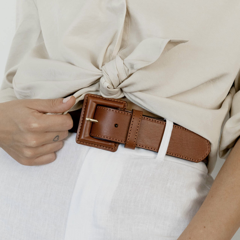 Wide women's leather belt with covered buckle in tan, worn over white linen pants with focus on the buckle - MONPIEL