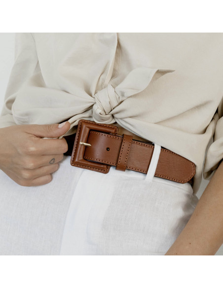 Wide women's leather belt with covered buckle in tan, worn over white linen pants with focus on the buckle - MONPIEL Wide women's leather belt with covered buckle in tan, worn over white linen pants with focus on the buckle - MONPIEL