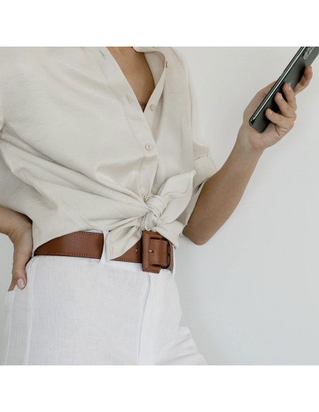 Wide women's leather belt with covered buckle in tan, shown in perspective over white linen pants - MONPIEL Wide women's leather belt with covered buckle in tan, shown in perspective over white linen pants - MONPIEL