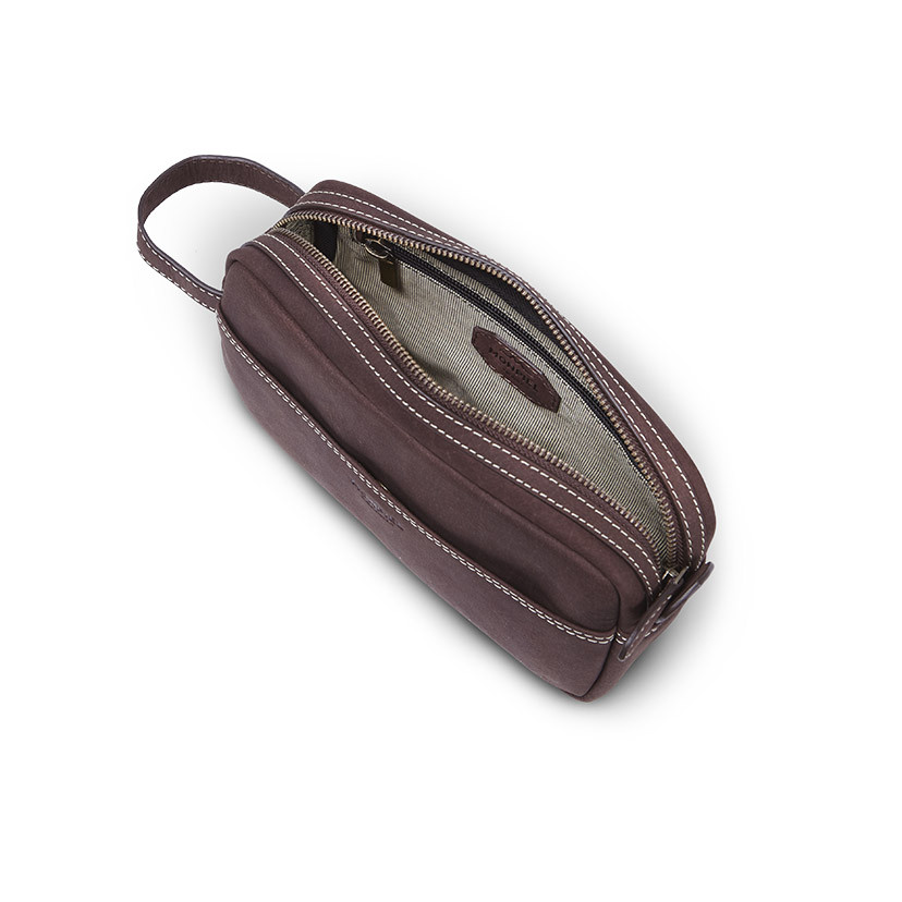 Brown leather men's toiletry bag, shown from above with open zipper and interior detail on a white background - MONPIEL