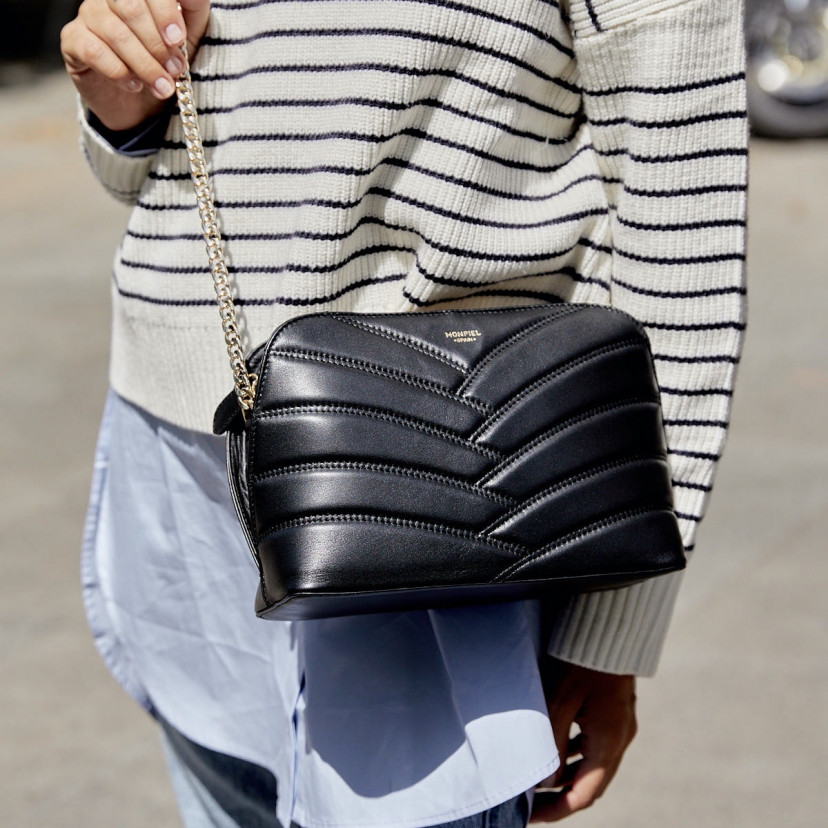 Black leather quilted bag with gold chain, worn crossbody on the outside - MONPIEL