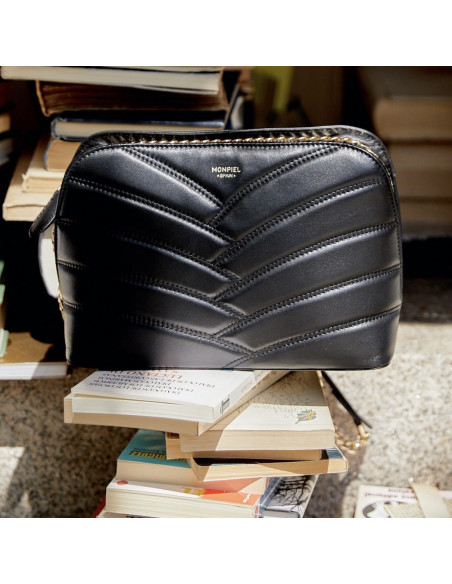 Bolso acolchado de piel con cadena oro en color negro con vista frontal apoyado sobre libros - MONPIEL Bolso acolchado de piel con cadena oro en color negro con vista frontal apoyado sobre libros - MONPIEL