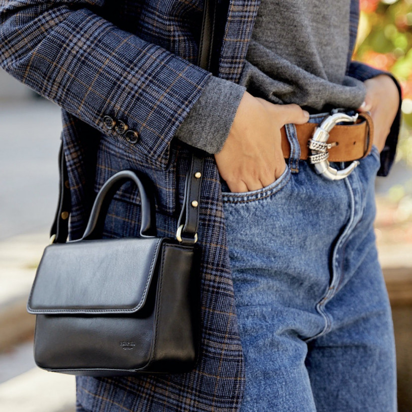 Small Armado leather bag in black, worn on the shoulder with a close-up shot, outdoor background - MONPIEL