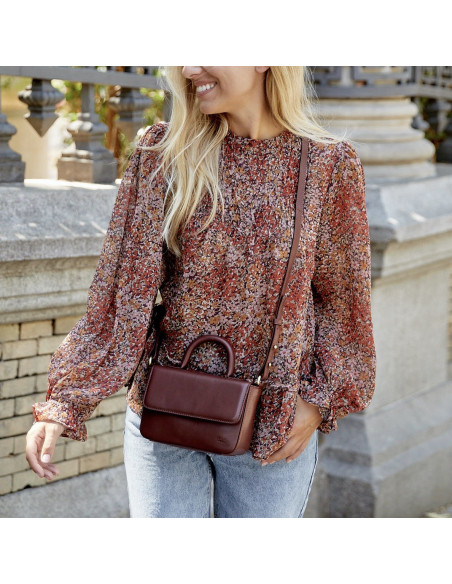 Small Armado leather bag in brown, worn crossbody, mid-shot outdoors - MONPIEL Small Armado leather bag in brown, worn crossbody, mid-shot outdoors - MONPIEL