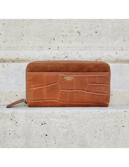 Portefeuille femme en cuir avec fermeture éclair couleur cuir, vue frontale sur un mur - MONPIEL