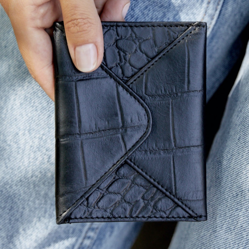 Leather envelope cardholder in black, shown in close-up held in hands - MONPIEL