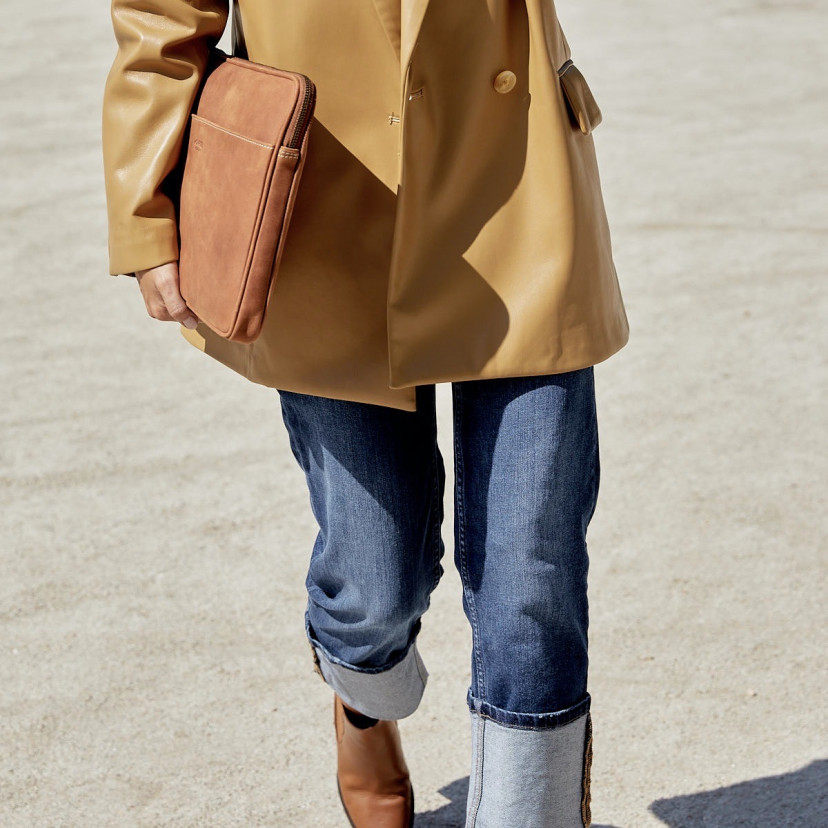 13" and 14"-inch leather laptop sleeve in tan, shown from the side held by hand with an outdoor background - MONPIEL
