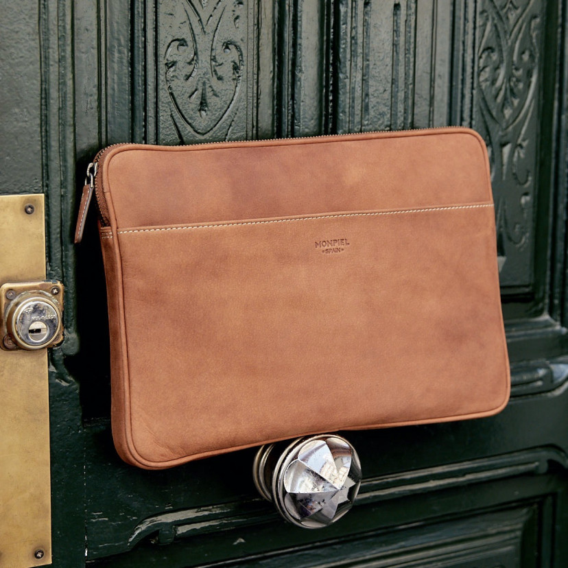 13" and 14"-inch leather laptop sleeve in tan, shown from the front resting on the door handle - MONPIEL