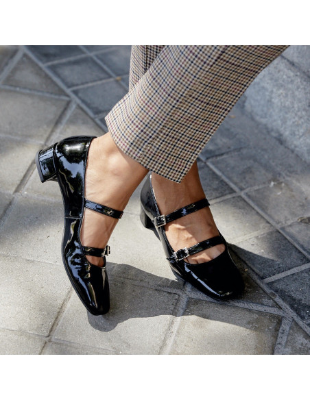 Mary Jane in vernice Lolina nere con gambe incrociate su sfondo esterno - MONPIEL