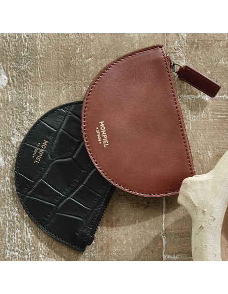 Monedero de piel media luna en color negro y color marrón apoyados sobre una mesa de madera - MONPIEL