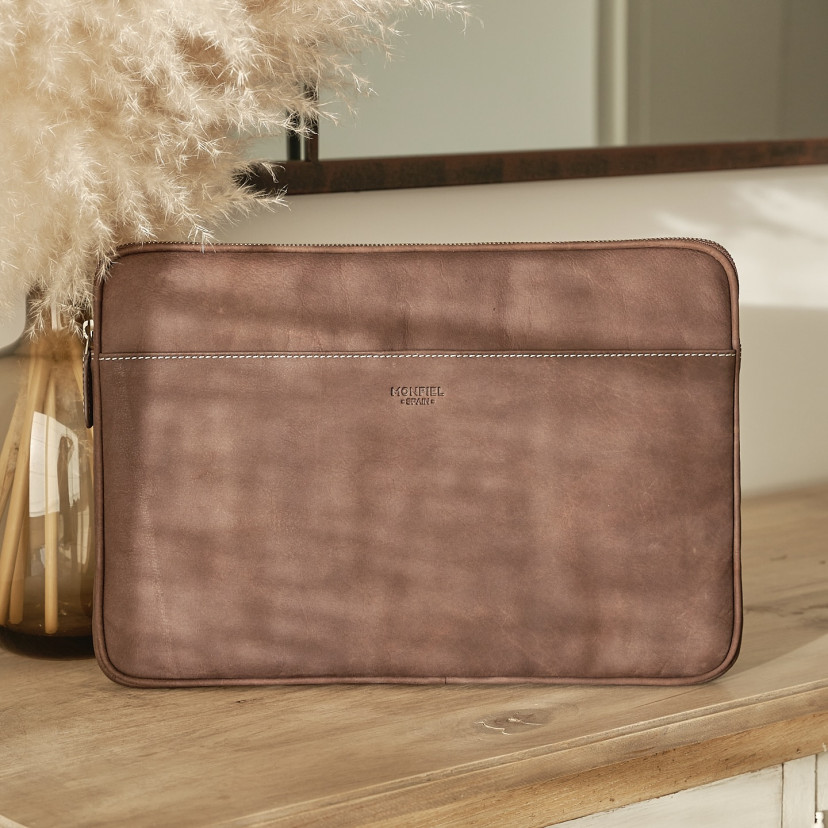 13" and 14"-inch leather laptop sleeve in brown, shown from the front with a mirror behind and a vase beside - MONPIEL