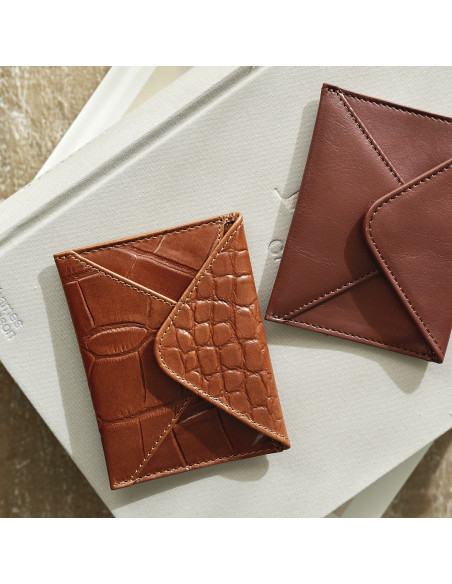 Porte-cartes en cuir en forme d'enveloppe marron et cuir reposant sur un livre avec vue de dessus - MONPIEL Porte-cartes en cuir en forme d'enveloppe marron et cuir reposant sur un livre avec vue de dessus - MONPIEL
