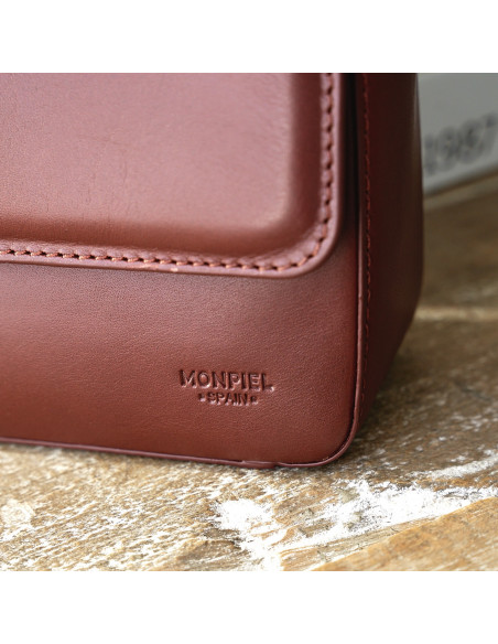 Small Armado leather bag in brown, with logo detail in close-up focus - MONPIEL Small Armado leather bag in brown, with logo detail in close-up focus - MONPIEL