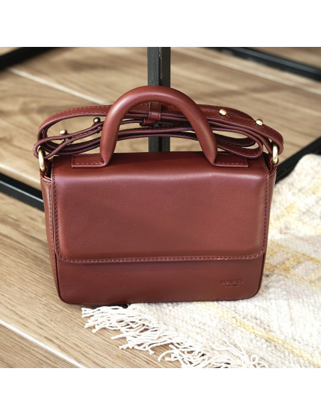 Small Armado leather bag in brown, shown from the front resting on a carpet - MONPIEL Small Armado leather bag in brown, shown from the front resting on a carpet - MONPIEL