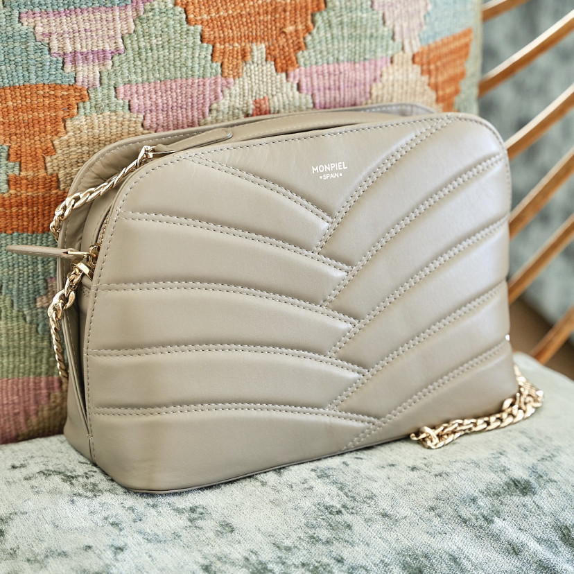 Taupe leather quilted bag with gold chain, shown from the front resting on a cushion - MONPIEL
