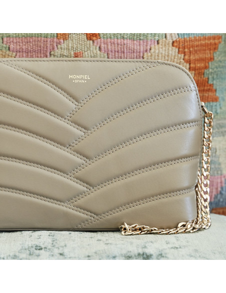 Borsa in pelle trapuntata con catena dorata color topo in primo piano con dettaglio del logo appoggiata su un cuscino - MONPIEL Borsa in pelle trapuntata con catena dorata color topo in primo piano con dettaglio del logo appoggiata su un cuscino - MONPIEL