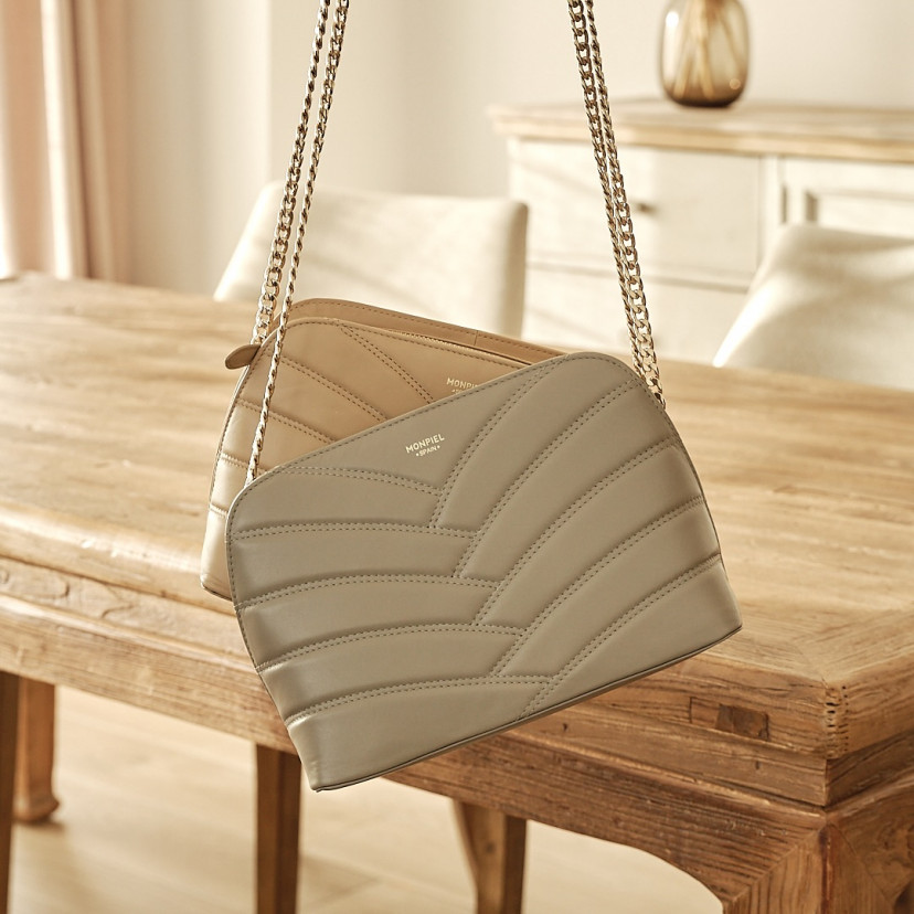 Bolsa acolchoada de couro com corrente dourada na cor taupe com bolsa bege ao fundo - MONPIEL