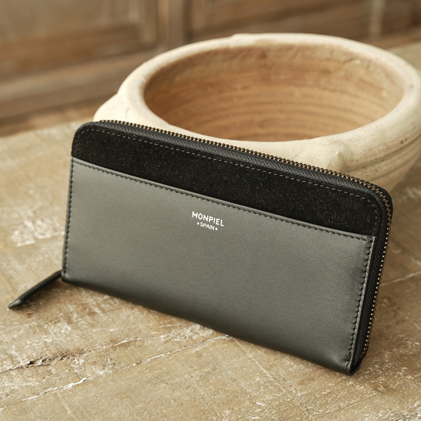 Women's leather zipper wallet in black, shown in perspective resting on ceramic - MONPIEL
